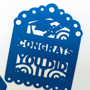 May include: Blue paper cutout with a graduation cap and diploma design. The text "Congrats You Did It" is cut out of the paper.