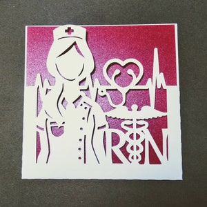 May include: A white paper card with a red background. The card features a cutout design of a nurse with a stethoscope and the letters "RN".