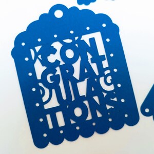 May include: Blue paper party banner with the words "Congratulations" cut out in a decorative font.