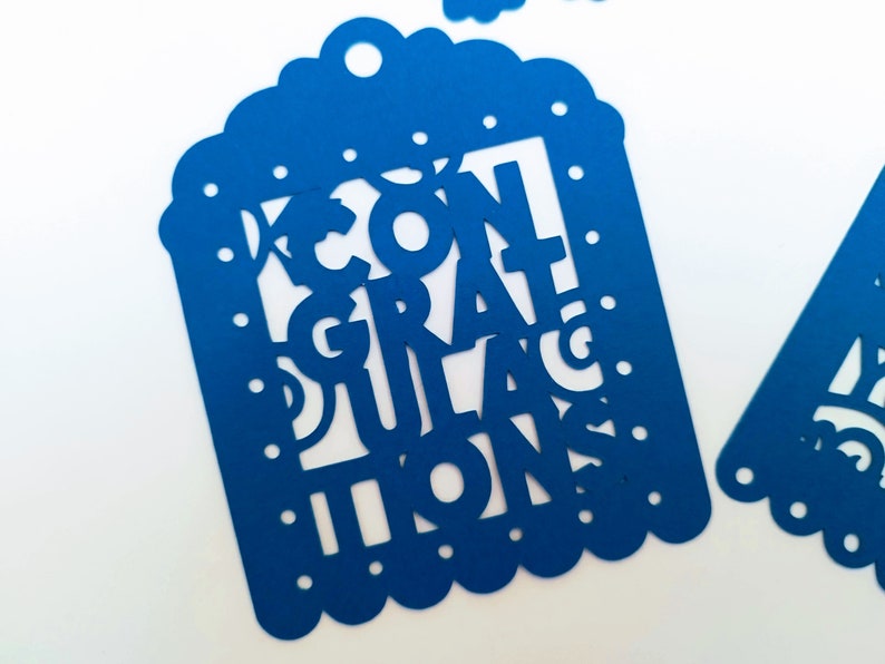 May include: Blue paper party banner with the words "Congratulations" cut out in a decorative font.