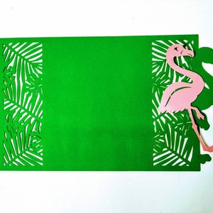 May include: A green card with a pink flamingo cutout and a tropical leaf design. The card is blank and can be used for a variety of purposes.