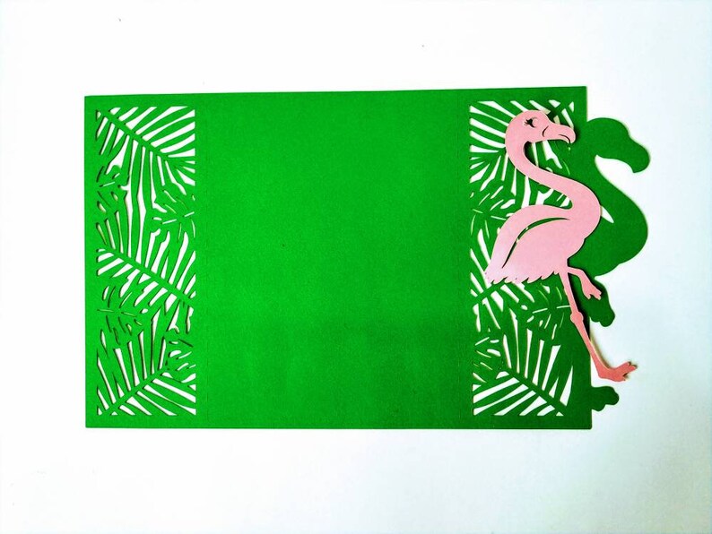 May include: A green card with a pink flamingo cutout and a tropical leaf design. The card is blank and can be used for a variety of purposes.