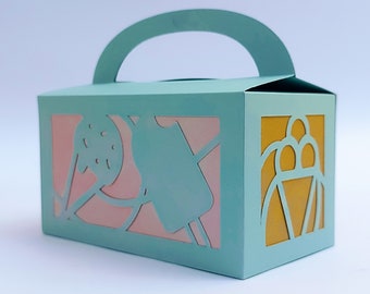 May include: A light blue cardboard box with a handle. The box has cut-out designs of ice cream cones and a scoop of ice cream on the front and side. The cut-outs reveal pink and yellow paper inside the box.