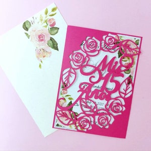 May include: Pink invitation with a cut-out design of roses and the text "Mis 15 Anos" in a decorative font.