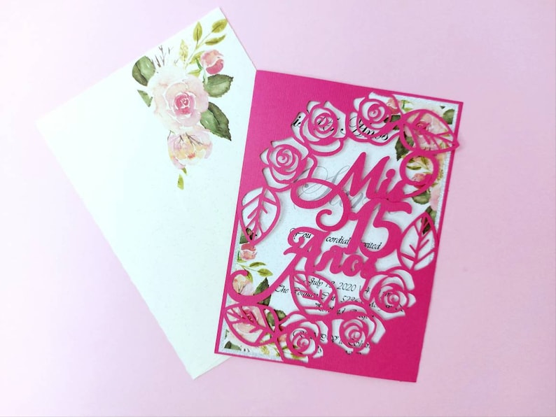 May include: Pink invitation with a cut-out design of roses and the text "Mis 15 Anos" in a decorative font.