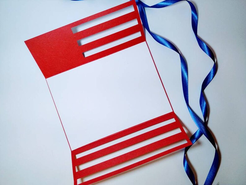 May include: A red card with white stripes cut out, folded in half, with a blue ribbon on a white background.