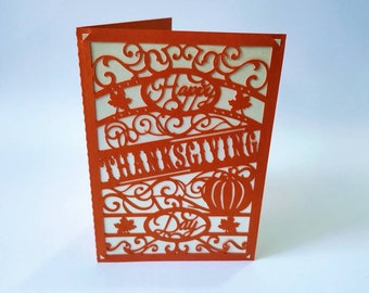 Könnte beinhalten: Orangefarbene Karte mit weißem Hintergrund und einem ausgeschnittenen Design. Die Karte sagt "Happy Thanksgiving Day" mit einem Kürbis und Herbstblättern.