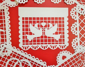 May include: White paper cutouts of doves with a heart above them, on a red background. The doves are inside a grid pattern, and the edges of the paper are scalloped.