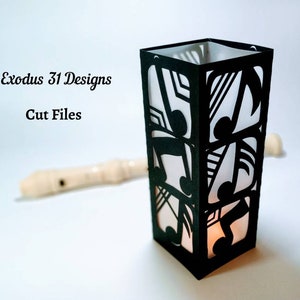 May include: Black paper lantern with a cut-out design of musical notes. The lantern is lit from within, casting a warm glow. Exodus 31 Designs Cut Files.