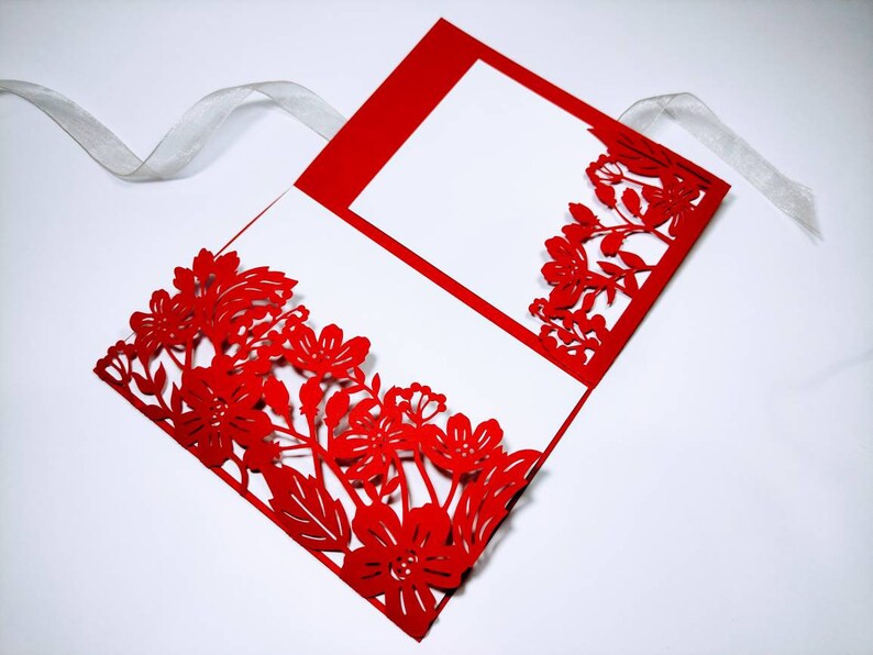 Pu&ograve; includere: Invito di nozze rosso tagliato al laser con un design floreale. L'invito &egrave; piegato a met&agrave; e ha un interno bianco.