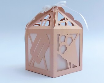 May include: A light pink, decorative paper box with a white ribbon. The box has a cut-out design of an ice cream cone and popsicle.