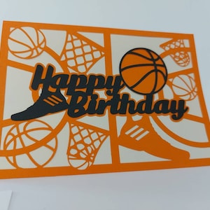 May include: Orange card with a black cut-out design of a basketball, a shoe, and a net. The card says "Happy Birthday" in black.