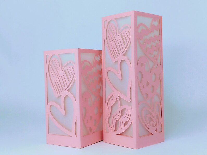 K&ouml;nnte beinhalten: Zwei rosa Papierlaternen mit ausgeschnittenen Herzen. Die Laternen sind unterschiedlich gro&szlig; und haben unterschiedliche Herzdesigns.