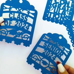 May include: Four blue paper cut-out decorations for a graduation party. The decorations feature the text "Class of 2024", "Senior 2024", "Congratulations", and "You Did It!"