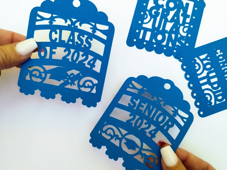 May include: Four blue paper cut-out decorations for a graduation party. The decorations feature the text "Class of 2024", "Senior 2024", "Congratulations", and "You Did It!"