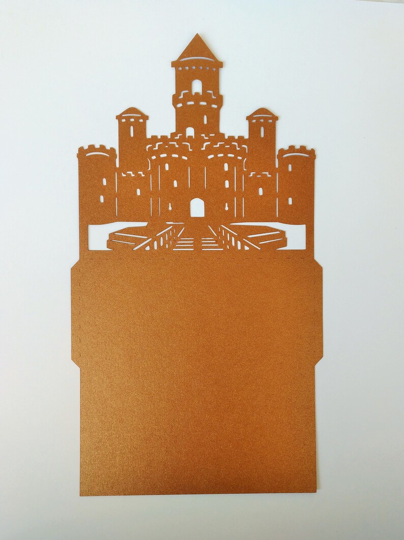 May include: A brown paper castle-shaped card with a cut-out design. The card is blank inside and can be used for invitations, announcements, or other special occasions.