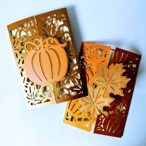 May include: Two folded cards with intricate cut-out designs. One card features a pumpkin with a gold background, while the other card has a brown background with leaves.