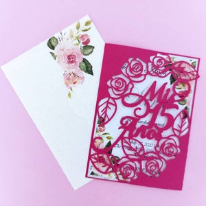 May include: A pink invitation with a cut-out design of roses and leaves. The text "Mis 15 Anos" is written in a decorative font.