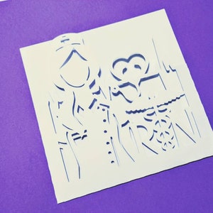 May include: White paper with a detailed cutout design of a couple holding hands. The design is intricate and includes a heart shape.