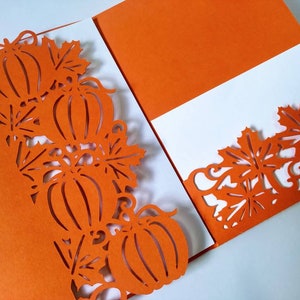 May include: Orange card with a white insert. The card has a cut-out design of pumpkins and leaves around the edges.