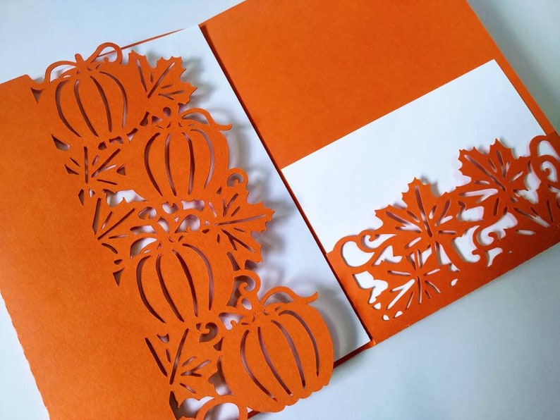 May include: Orange card with a white insert. The card has a cut-out design of pumpkins and leaves around the edges.