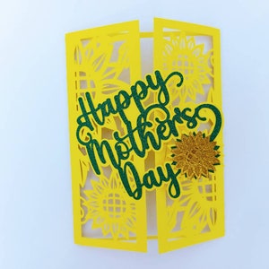 Op de afbeelding: Een gele kaart met een groene glitter-uitsparing van de woorden "Happy Mother's Day" en een gouden glitter-zonnebloem. De kaart is versierd met een zonnebloemmotief.