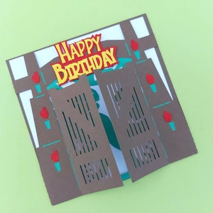 May include: A brown paper card with a pop-up design of a saloon style swinging door. The door is open and the card says "Happy Birthday" in yellow letters.