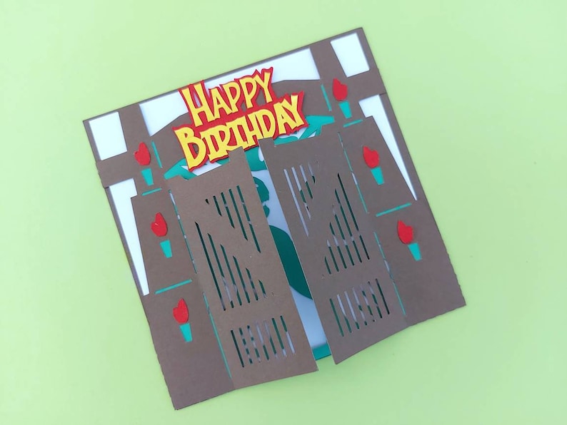 May include: A brown paper card with a pop-up design of a saloon style swinging door. The door is open and the card says "Happy Birthday" in yellow letters.