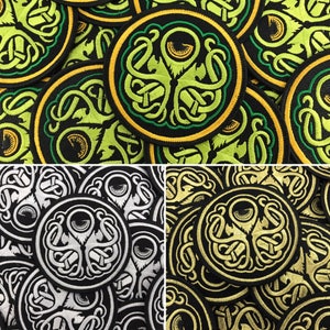 May include: A collection of embroidered patches featuring a green, yellow, and black design of a stylized eye with tentacles. The patches are circular and have a black outline.
