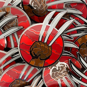 May include: A close-up of a red and white enamel pin featuring a brown fist with three silver claws. The background is a red and white cracked pattern.