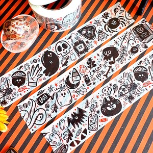 May include: Halloween-themed washi tape rolls with black and white illustrations of ghosts, skulls, spiders, and pumpkins. The tape features the text "Creep it Real" and "Boo". The tape is on a black and orange striped background.