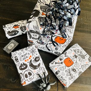 May include: Four black and white wrapping paper sheets with a spooky Halloween theme. The paper features illustrations of ghosts, pumpkins, spiders, and the text "Creep It Real".
