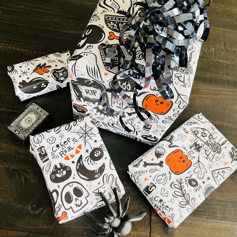 May include: Four black and white wrapping paper sheets with a spooky Halloween theme. The paper features illustrations of ghosts, pumpkins, spiders, and the text "Creep It Real".