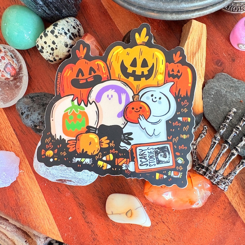 May include: A Halloween-themed sticker featuring cartoon pumpkins, ghosts, and candy. The sticker has the text "SCARY STORIES" on a book. The design includes orange, purple, and white elements, with a black outline.