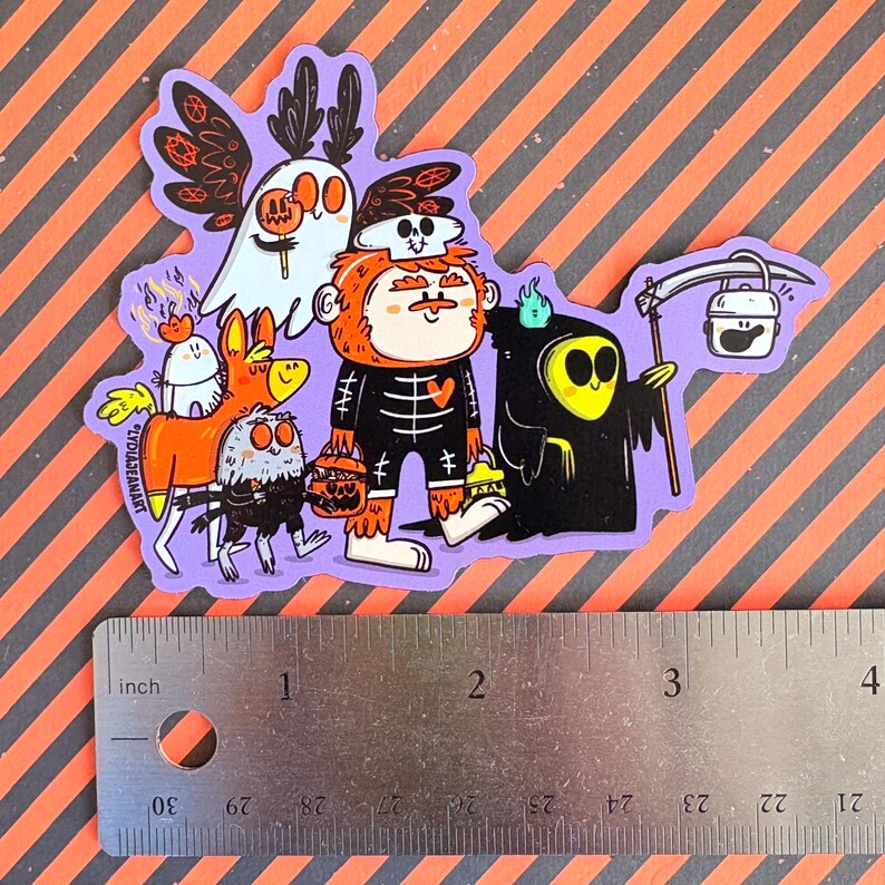 May include: A purple sticker featuring a group of cartoon Halloween characters. The characters include a ghost, a skeleton, a grim reaper, and other spooky creatures. The sticker is approximately 3 inches wide.