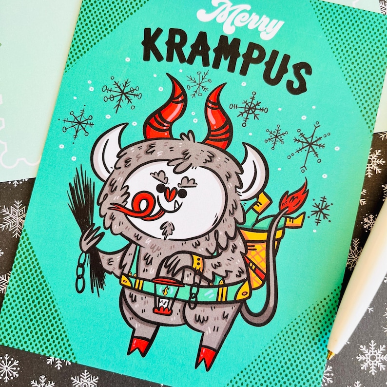 May include: A teal blue greeting card with a cartoon illustration of Krampus, a Christmas demon, with red horns, a chain, and a lantern. The card has a white polka dot pattern and the text "Merry Krampus".