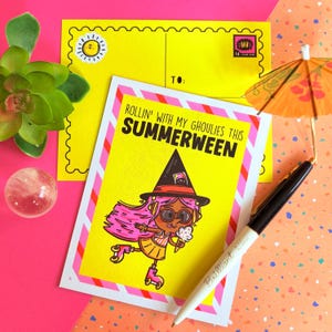 May include: A yellow greeting card with the text "ROLLIN' WITH MY GHOULIES THIS SUMMERWEEN" and an illustration of a witch on roller skates. A yellow envelope and a pen are also in the image.