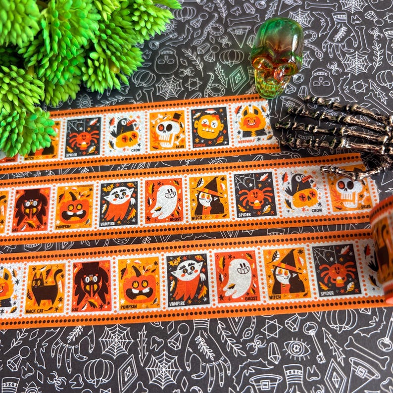 Puede incluir: Un rollo de cinta decorativa washi con un patr&oacute;n repetitivo de cuadrados naranjas y negros con tem&aacute;tica de Halloween. Cada cuadrado muestra un personaje o icono &uacute;nico, incluyendo un fantasma, bruja, vampiro, calabaza, ara&ntilde;a y una calavera.