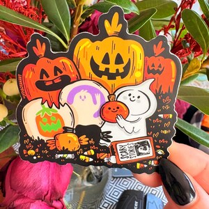 May include: A Halloween-themed sticker featuring cartoon pumpkins, ghosts, and candy corn. The sticker includes the text "Scary Stories" on a small book. The pumpkins are orange and yellow with carved faces.