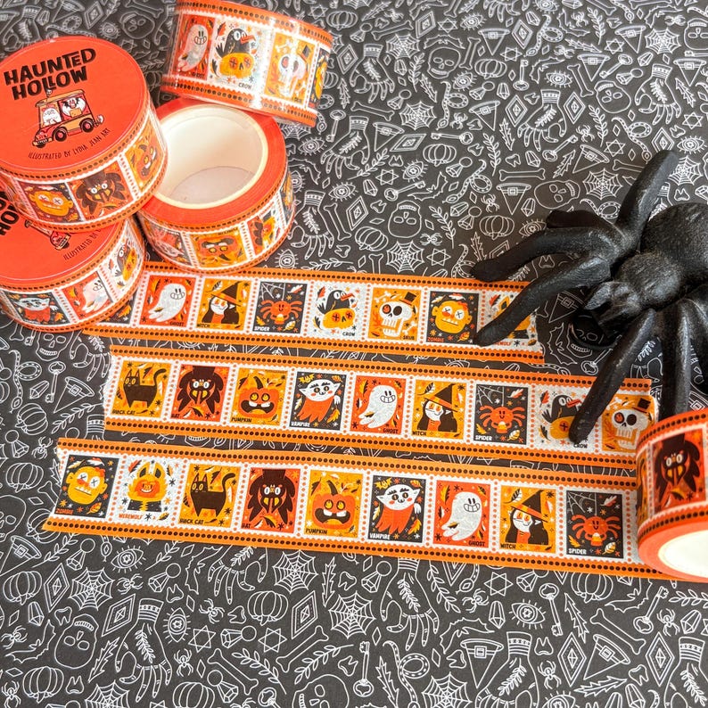 Puede incluir: Tres rollos de cinta decorativa washi naranja y blanca con un patr&oacute;n repetitivo de personajes de Halloween que incluye fantasmas, calabazas, murci&eacute;lagos y brujas. El texto Haunted Hollow est&aacute; impreso en el rollo superior con un coche de dibujos.