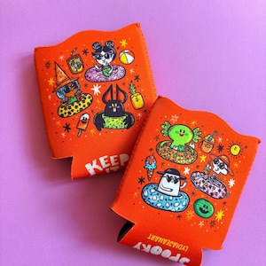 May include: Two orange drink koozies with colorful illustrations of spooky characters in inner tubes. One koozie has the word "KEEP" printed in white. The other koozie has the word "SPOOKY" and the artist's name printed in white.