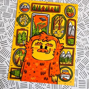 May include: A cartoon illustration of a furry orange creature with a yellow face and a jar of peanut butter labeled "Chunky". The creature is surrounded by small framed pictures of various scenes, including a UFO, a forest, and mountains.