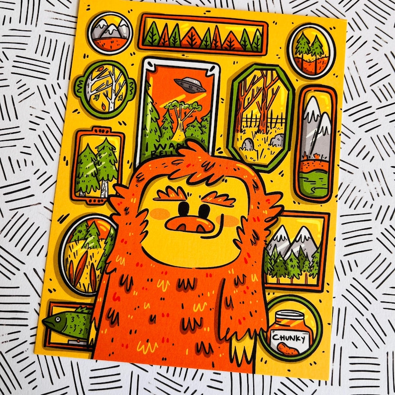 May include: A cartoon illustration of a furry orange creature with a yellow face and a jar of peanut butter labeled "Chunky". The creature is surrounded by small framed pictures of various scenes, including a UFO, a forest, and mountains.