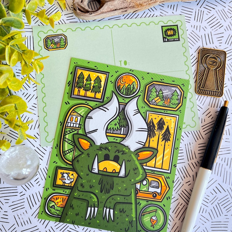 May include: A green monster with large horns and a toothy grin is surrounded by small framed illustrations of trees and a cabin. The postcard is green with a light green background and has a "HI" stamp in the top right corner.