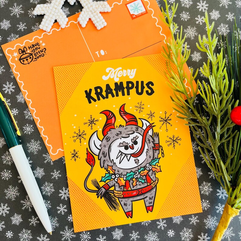 May include: A yellow postcard with a cartoon illustration of Krampus, a Christmas demon, with the text "Merry Krampus" on the front.
