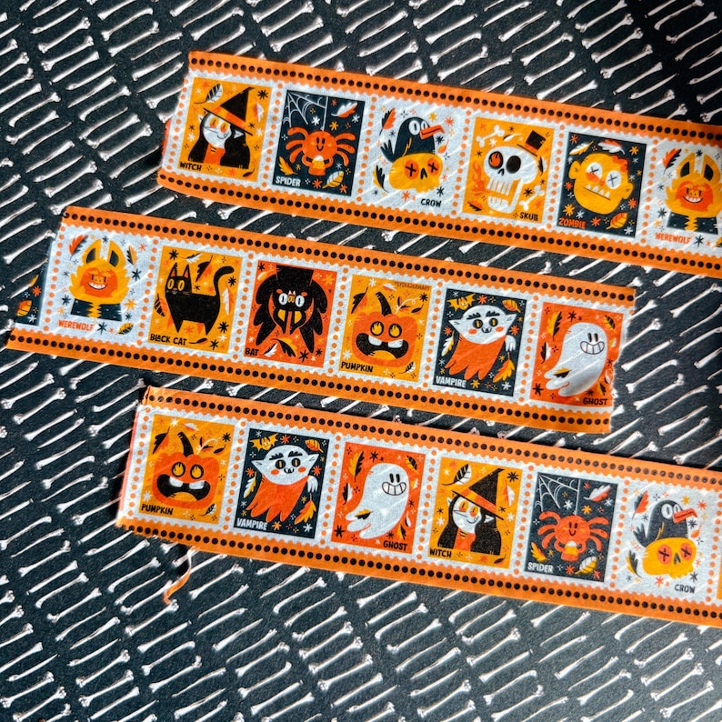 Puede incluir: Tres tiras de cinta decorativa con borde naranja que presentan ilustraciones cuadradas repetitivas de personajes de Halloween, incluyendo una bruja, ara&ntilde;a, cuervo, calavera, zombi, hombre lobo, gato negro, murci&eacute;lago, calabaza, vampiro y fantasma con sus nombres impresos debajo.