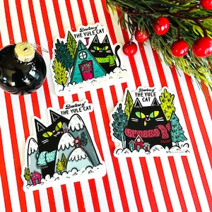 May include: Three black cat stickers with a winter holiday theme. Each sticker features a black cat wearing a red and black scarf and the text "Beware of the Yule Cat".