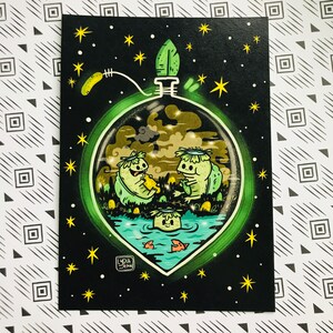 May include: A green glass orb with a glowing green rim, filled with a whimsical scene of two green creatures with flower crowns, sitting in a pond with a small creature swimming in the water. The orb is surrounded by a black background with yellow stars.