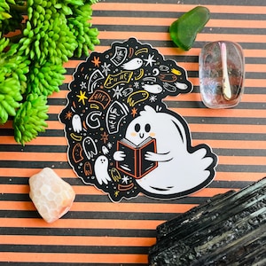 Puede incluir: Un fantasma blanco con una cara amigable está leyendo un libro rojo y negro. El fantasma está rodeado de una ilustración en blanco y negro de estrellas, remolinos y otros fantasmas.