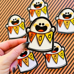 May include: Five white ghost stickers with orange and yellow bunting that reads "BOO" on each. The ghosts are smiling and have black eyes.